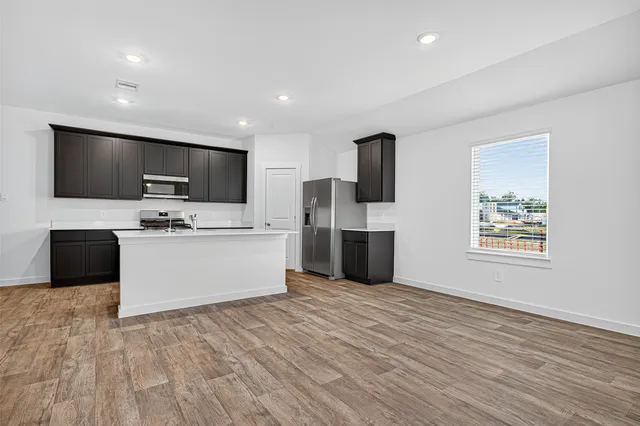 a large kitchen with stainless steel appliances a large counter top a stove a microwave a sink and cabinets