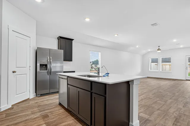 a kitchen with stainless steel appliances granite countertop a sink a refrigerator and a stove