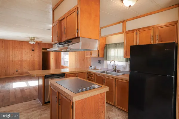 a kitchen with stainless steel appliances granite countertop a refrigerator a stove and a sink with wooden floor