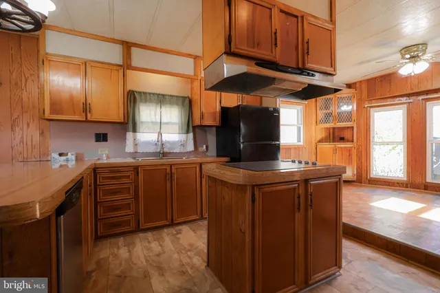 a kitchen with stainless steel appliances kitchen island granite countertop a refrigerator a stove and a sink with wooden floor