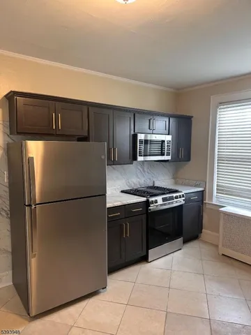 a kitchen with granite countertop a refrigerator and a stove top oven
