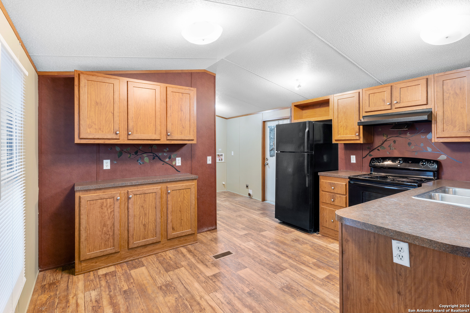 a kitchen with stainless steel appliances granite countertop a refrigerator a stove and a sink with wooden floors