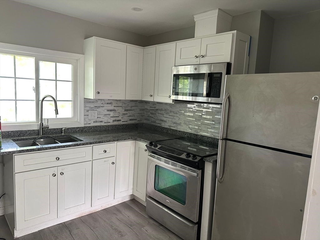 465 North Main Street, Unit 2 Randolph, MA 02368 - Photo 1 of 4 a kitchen with granite countertop white cabinets white stainless steel appliances and sink
