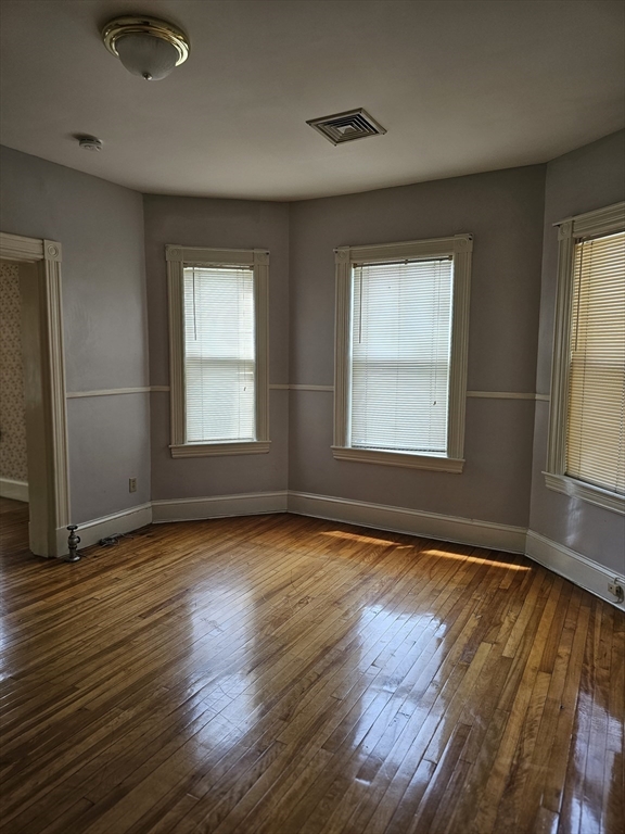404 Stevens Street, Unit 2 Lowell, MA 01851 - Photo 7 of 12 an empty room with wooden floor and windows