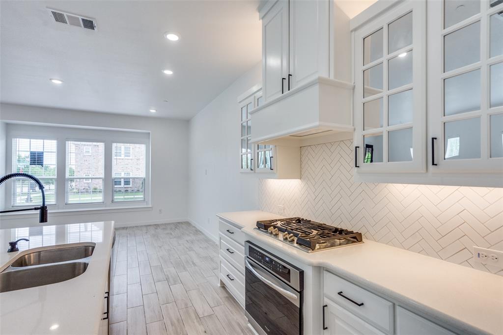 7207 Switchgrass Road Frisco, TX 75033 - Photo 12 of 26 a kitchen with granite countertop a sink a stove cabinets and wooden floor