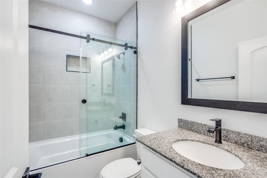 7207 Switchgrass Road Frisco, TX 75033 - Photo 21 of 26 a bathroom with a granite countertop sink toilet mirror and shower