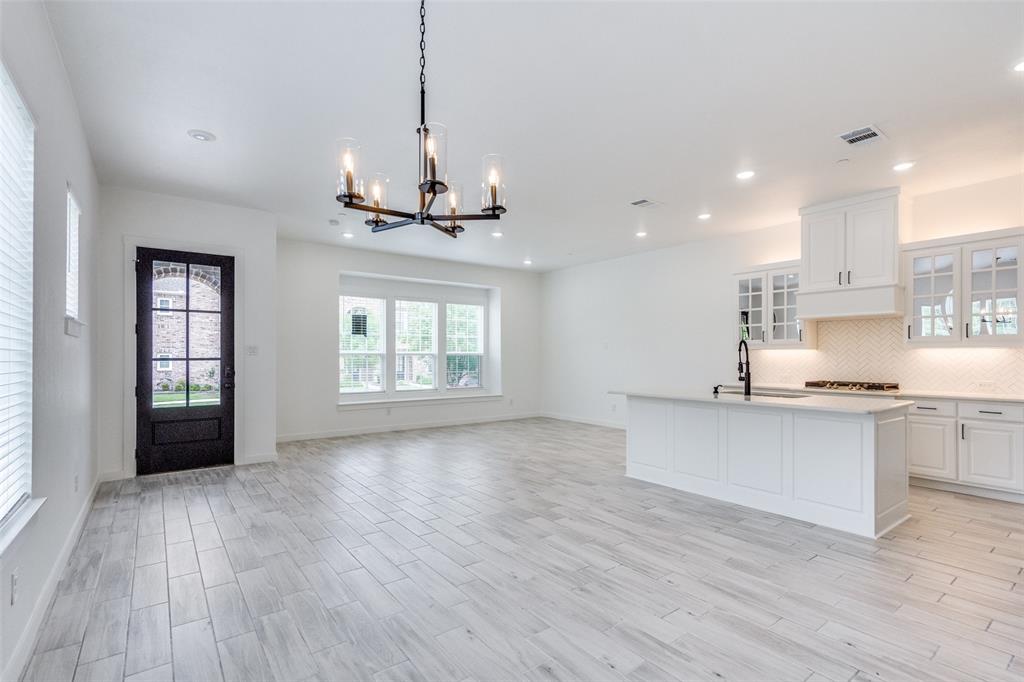 7207 Switchgrass Road Frisco, TX 75033 - Photo 9 of 26 a open kitchen with stainless steel appliances granite countertop a stove a sink dishwasher a refrigerator and a wooden floor