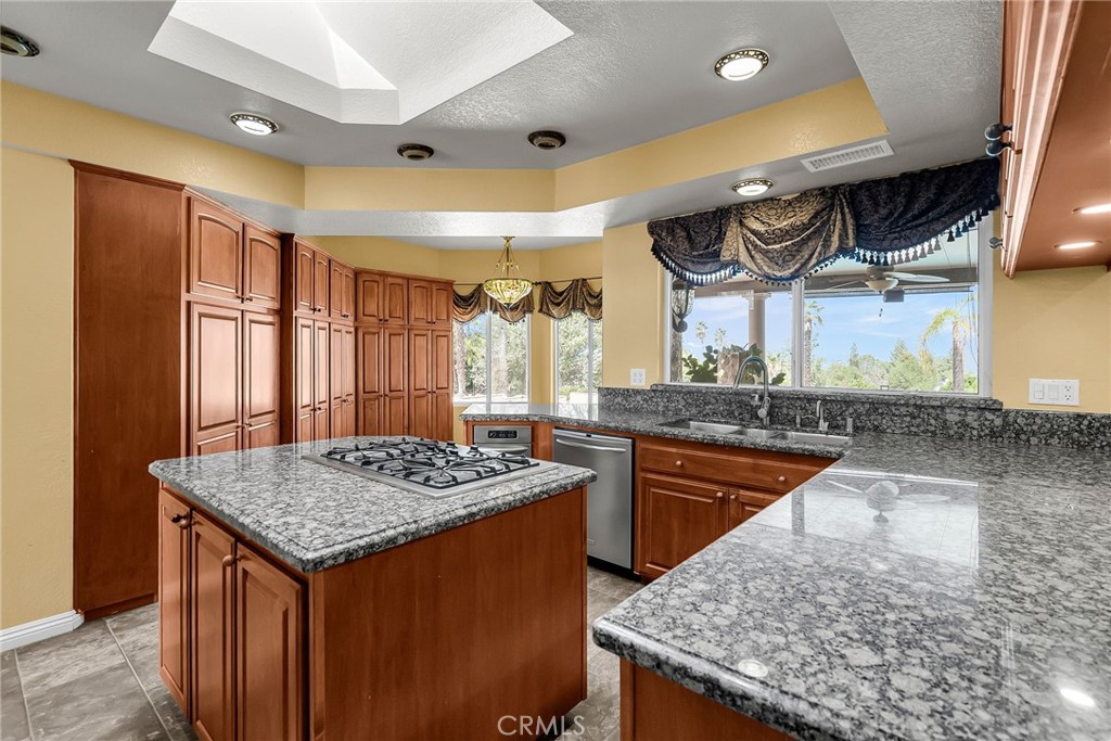1249 Coronet Drive Riverside, CA 92506 - Photo 11 of 57 a kitchen with granite countertop kitchen island stainless steel appliances a sink stove and cabinets
