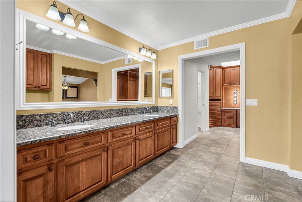 1249 Coronet Drive Riverside, CA 92506 - Photo 22 of 57 a bathroom with a granite countertop sink mirror and cabinets
