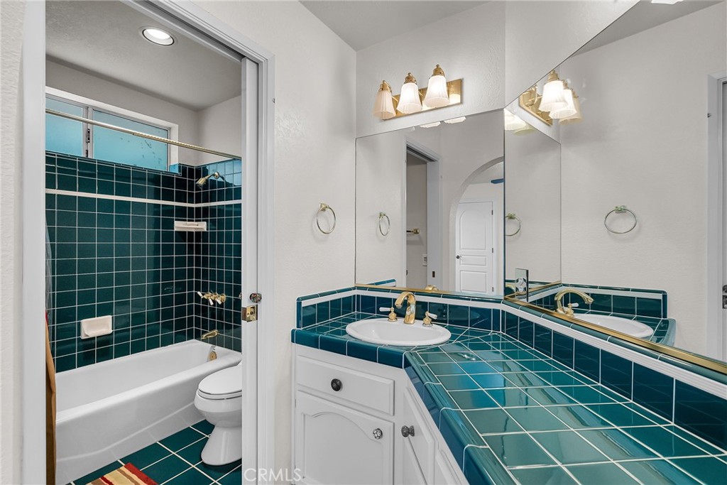 1249 Coronet Drive Riverside, CA 92506 - Photo 32 of 57 a bathroom with a sink a toilet a mirror a vanity a bathtub and shower