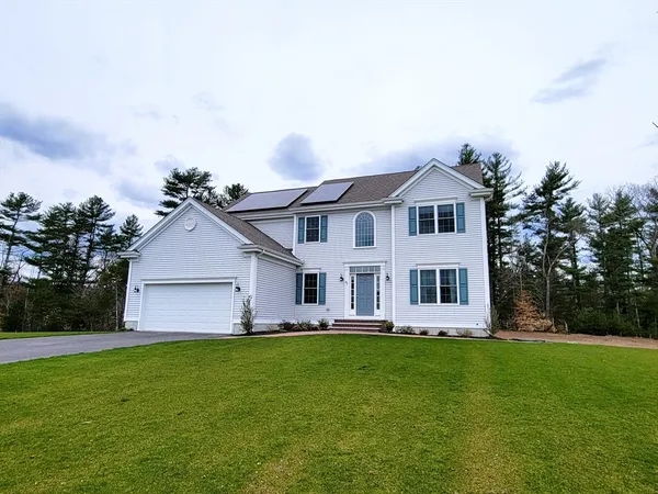 a front view of a house with a garden and trees