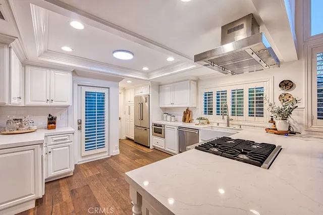a large kitchen with cabinets wooden floor and stainless steel appliances