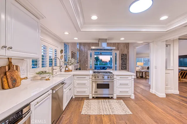 a large white kitchen with stainless steel appliances granite countertop a stove and a sink