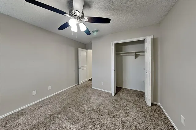 an empty room with closet and a ceiling fan