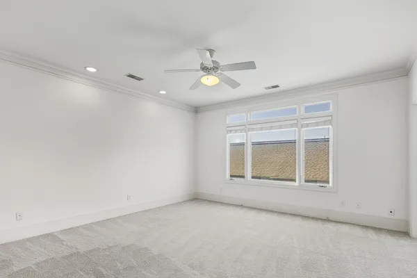 an empty room with chandelier fan and windows