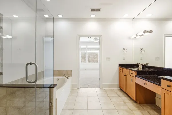 a spacious bathroom with a granite countertop sink a mirror and a shower