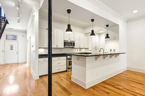 a kitchen with kitchen island a counter top space a sink wooden floor and appliances