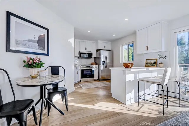 a kitchen with stainless steel appliances kitchen island granite countertop a dining table chairs and refrigerator