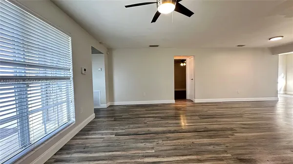 a view of a room with wooden floor and ceiling fan
