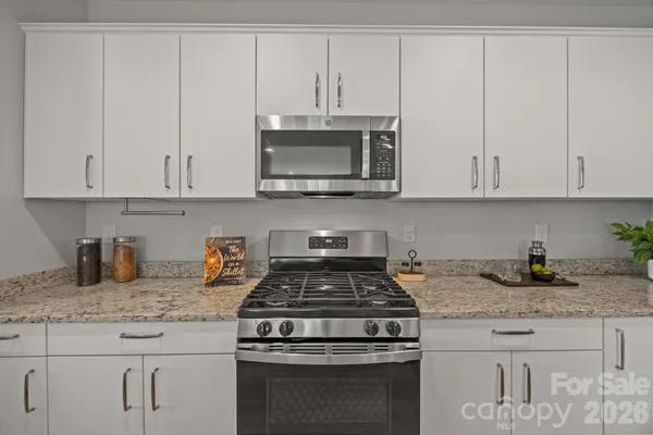 a kitchen with granite countertop a refrigerator and white cabinets