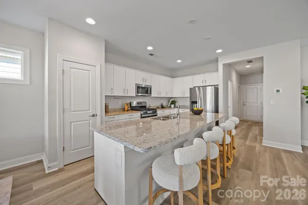 a large kitchen with granite countertop lots of counter space white cabinets and stainless steel appliances
