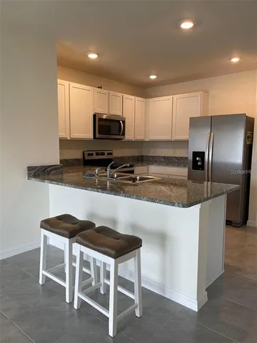 a kitchen with kitchen island granite countertop a table chairs microwave and refrigerator