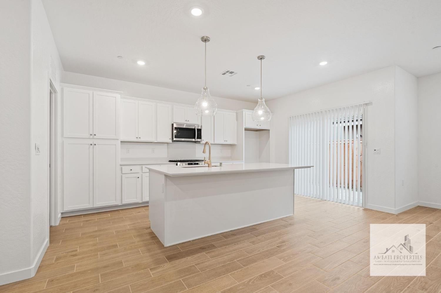 1017 Springtime Avenue Clovis, CA 93619 - Photo 3 of 13 a large white kitchen with kitchen island a sink a stove a refrigerator and white cabinets