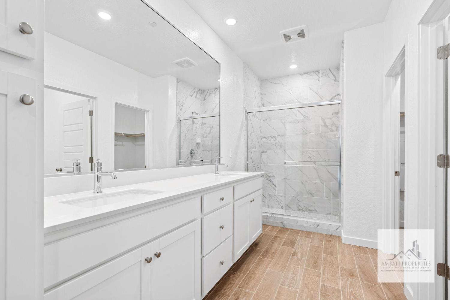 1017 Springtime Avenue Clovis, CA 93619 - Photo 8 of 13 a spacious bathroom with a double vanity sink a mirror and a shower