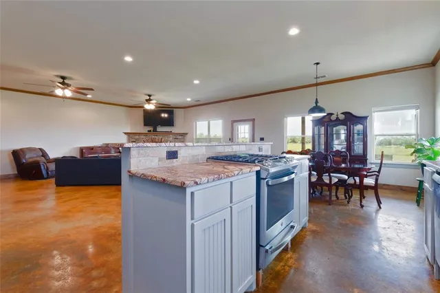 a kitchen with kitchen island a stove a table and chairs in it