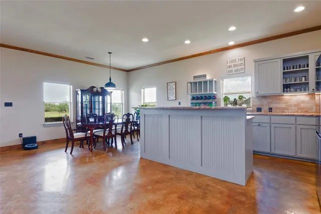 a kitchen with stainless steel appliances granite countertop a stove top oven a sink a dining table and chairs with wooden floor