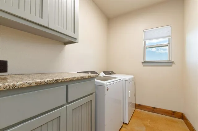 a utility room with granite countertop cabinets washer and dryer