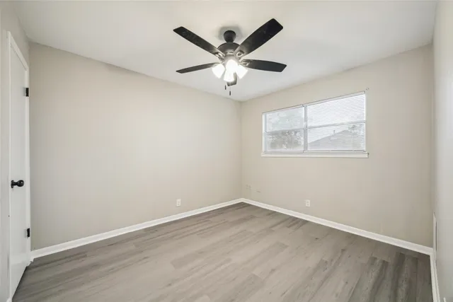 an empty room with wooden floor and ceiling fan