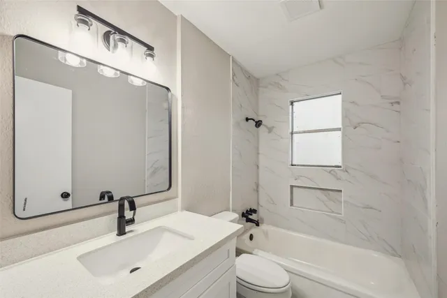 a bathroom with a bathtub shower sink vanity and toilet