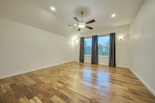 a view of an empty room with window and chandelier fan