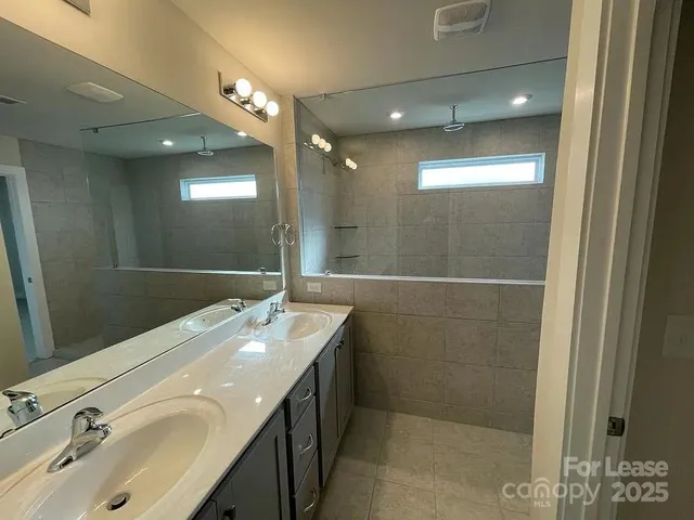 a bathroom with a double vanity sink a mirror and a shower