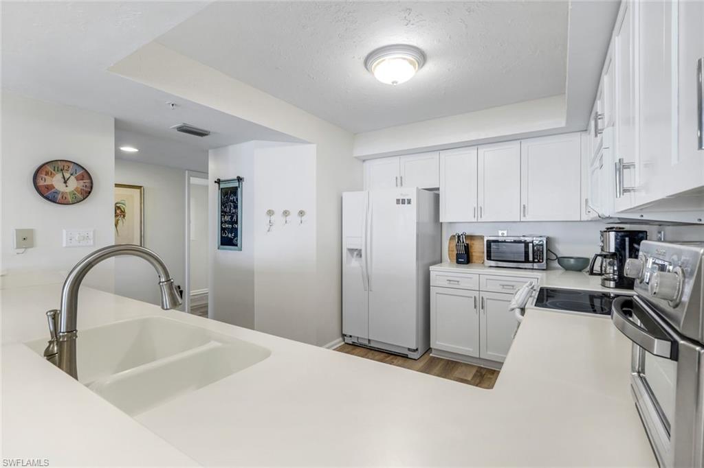 21 Bluebill Avenue, Unit B905 Naples, FL 34108 - Photo 11 of 35 a kitchen with refrigerator cabinets and a stove top oven