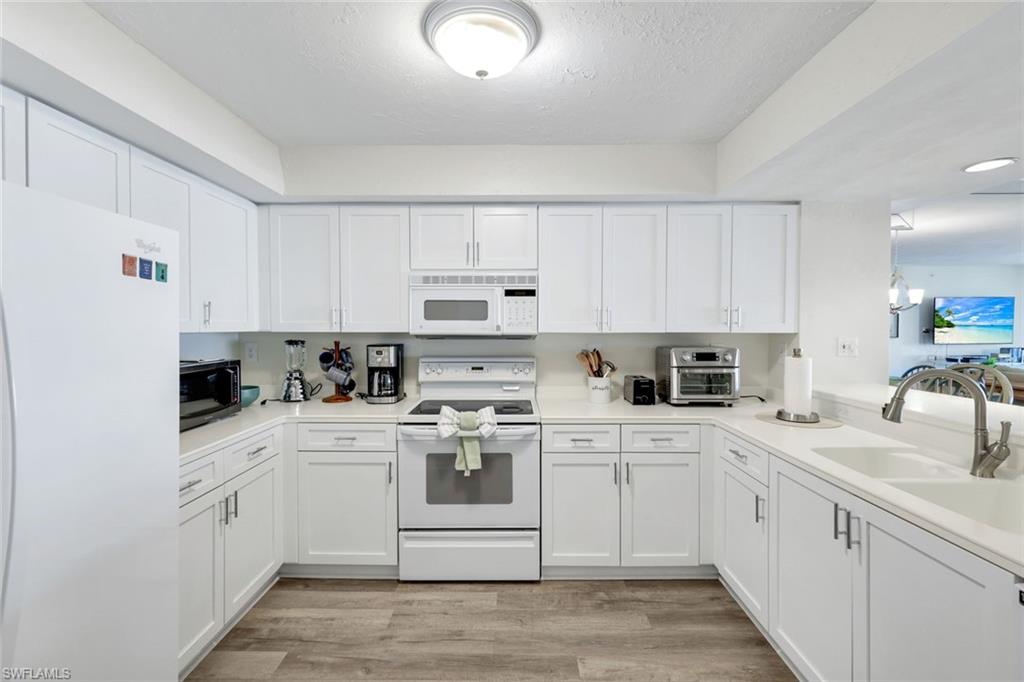 21 Bluebill Avenue, Unit B905 Naples, FL 34108 - Photo 9 of 35 a kitchen with white cabinets sink and white appliances
