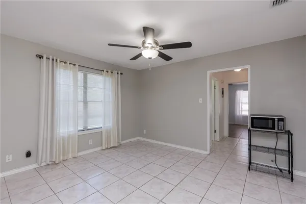a view of an empty room with a ceiling fan and window
