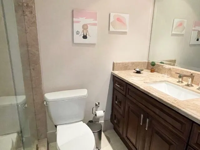 a bathroom with a granite countertop toilet sink and mirror