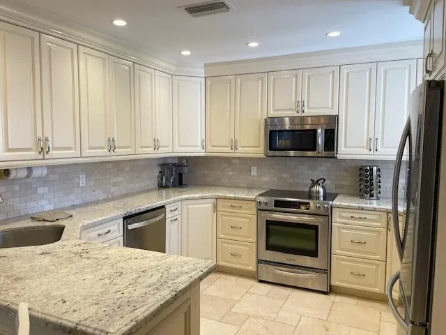 a kitchen with stainless steel appliances granite countertop a stove top oven microwave and refrigerator