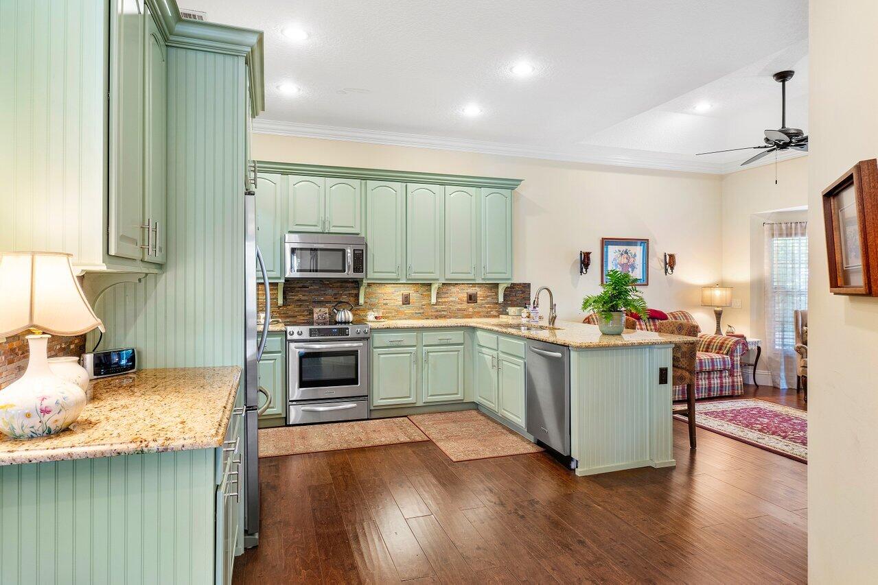 142 Mangrove Bay Way Jupiter, FL 33477 - Photo 6 of 17 a kitchen with granite countertop a stove top oven a sink dishwasher and a refrigerator with wooden floor