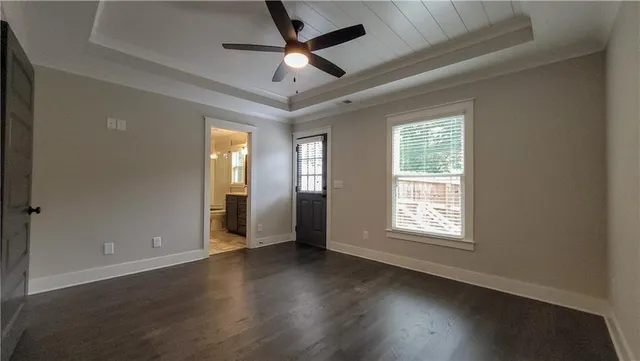 an empty room with wooden floor chandelier fan and windows