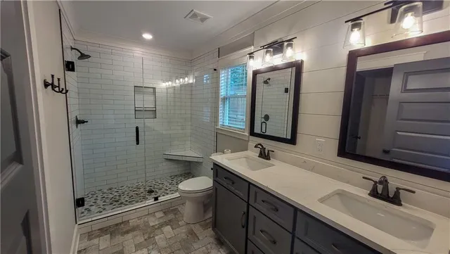 a bathroom with a double vanity sink toilet mirror and shower