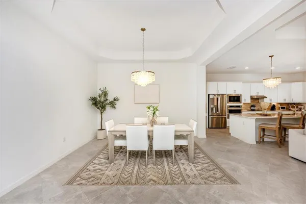 a kitchen with stainless steel appliances kitchen island granite countertop a refrigerator a sink dishwasher and white cabinets with wooden floor
