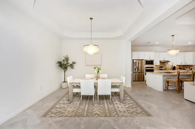 a kitchen with stainless steel appliances kitchen island granite countertop a refrigerator a sink dishwasher and white cabinets with wooden floor