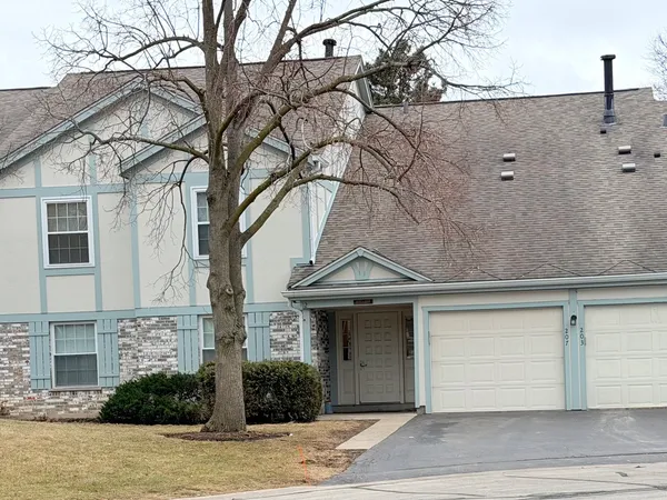 a front view of a house with garage and plants