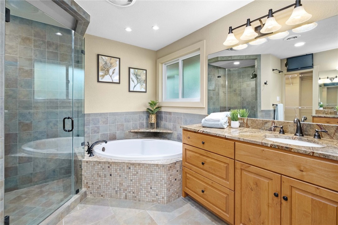 a bathroom with a granite countertop double vanity sink a mirror and a bathtub