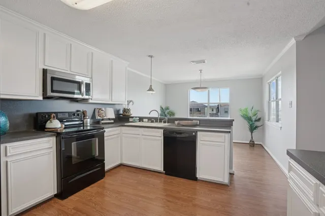 a kitchen with stainless steel appliances granite countertop a stove top oven a sink dishwasher and a refrigerator