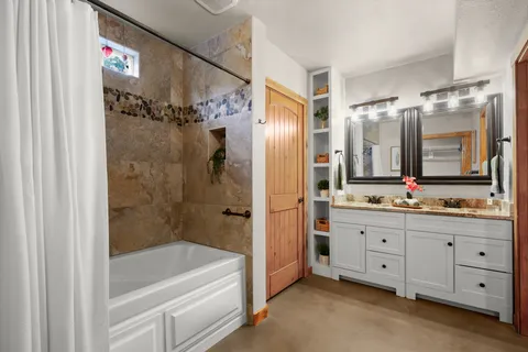 a bathroom with a granite countertop sink a mirror a bathtub and shower