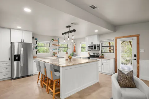 a kitchen with stainless steel appliances kitchen island granite countertop a refrigerator and a stove top oven